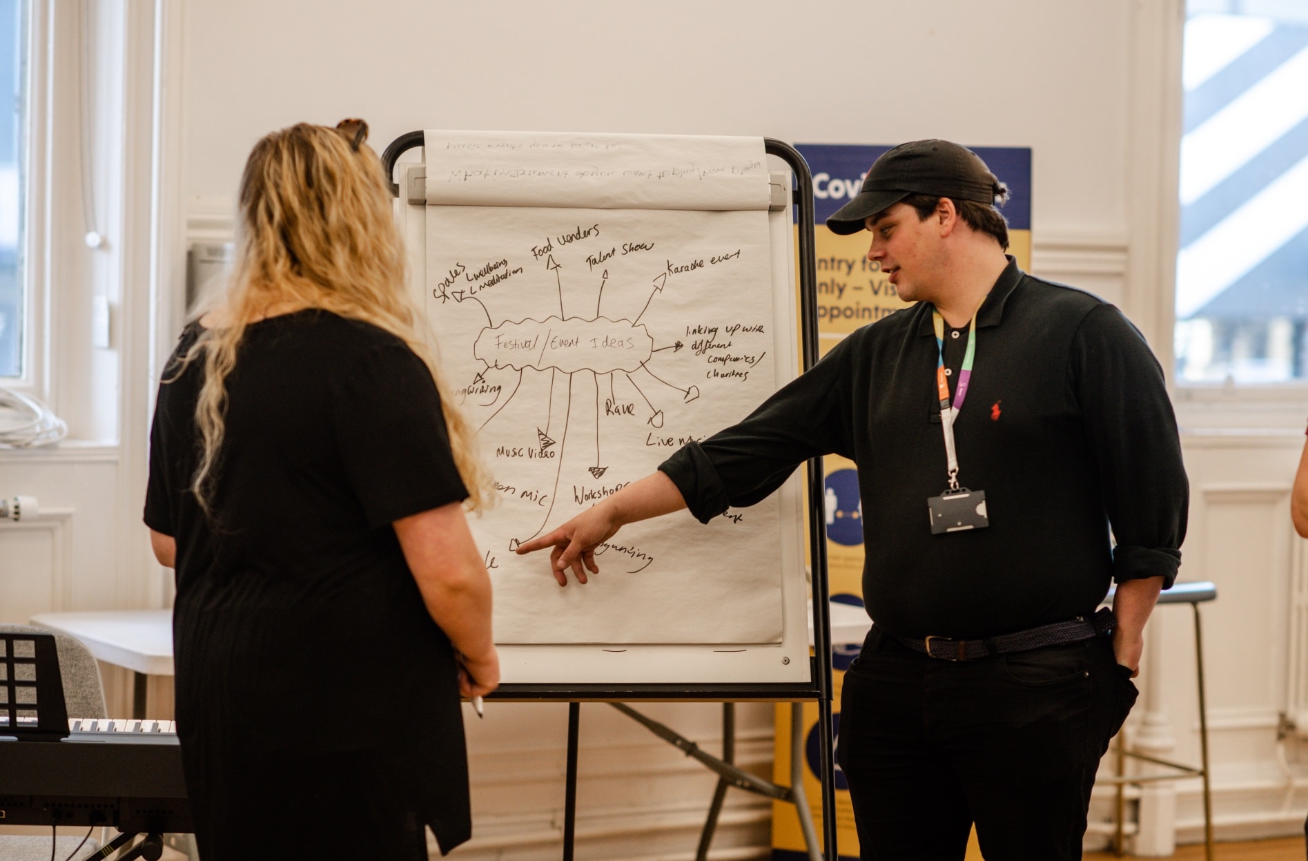 A woman looking at a man pointing at a flipchart with illustrations