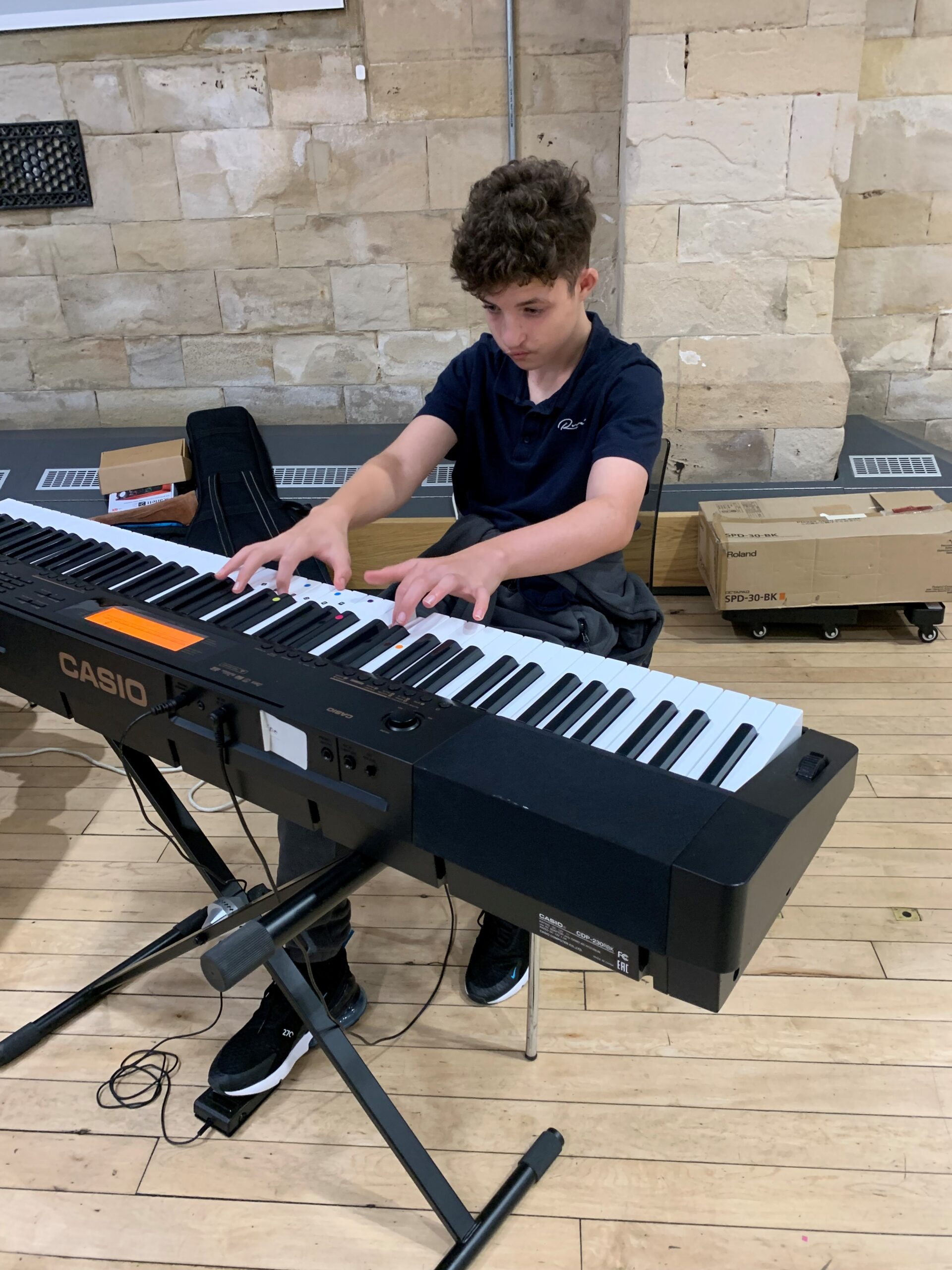 A boy sitting and playing a piano keyboard