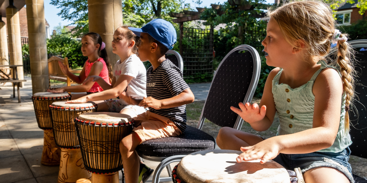 Four children drumming with their hands on djembe drums