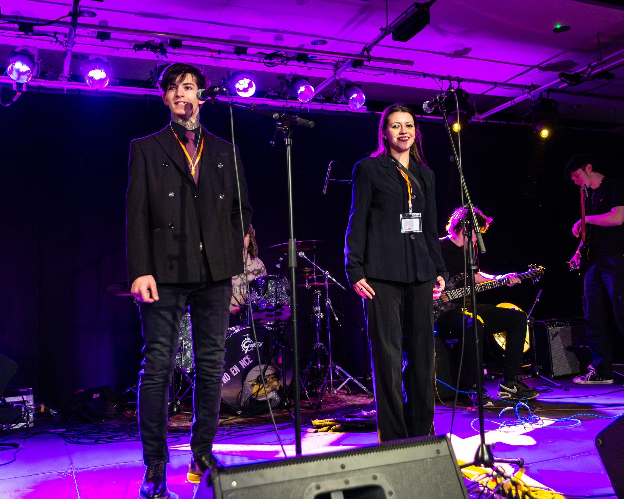 Two young people standing in front of mics on stage