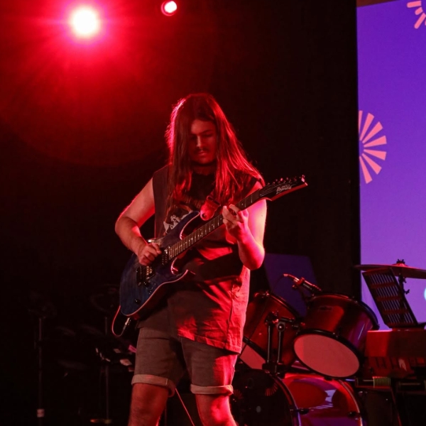 A young person playing an electric guitar on stage